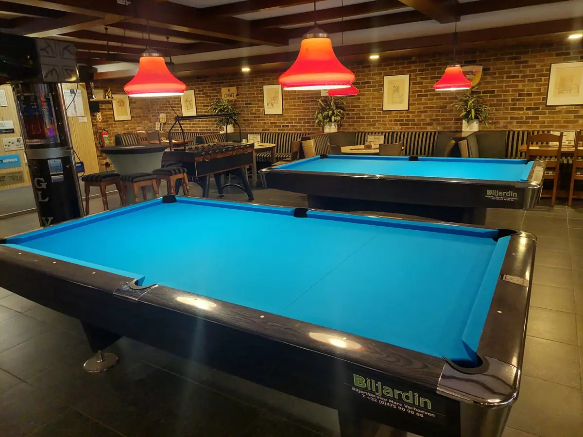 Twee pooltafels onder rode lampen bij Buulse